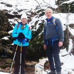 Two MCM members standing in front of a large rock with freshly fallen snow on the ground