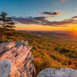 A view of a valley from atop a mountain at sunset