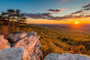 A view of a valley from atop a mountain at sunset