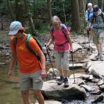 Members of MCM crossing a stream using by stepping on large rocks